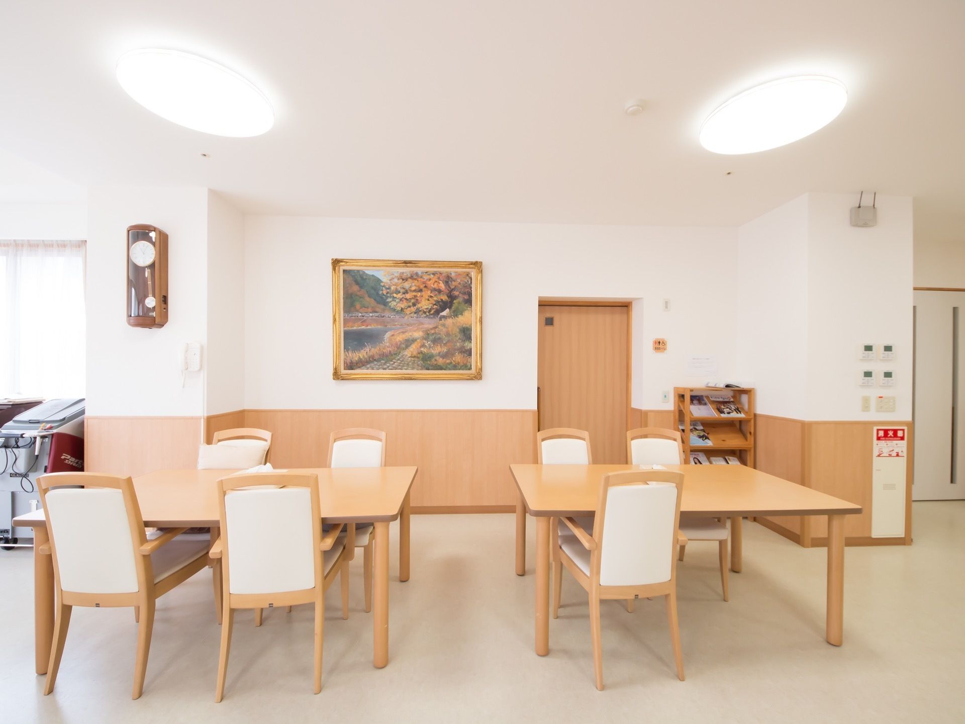 ２つのダイニングセットが並べて置いてある。壁に振り子の時計と金縁の大きな額に入った絵が飾られている。