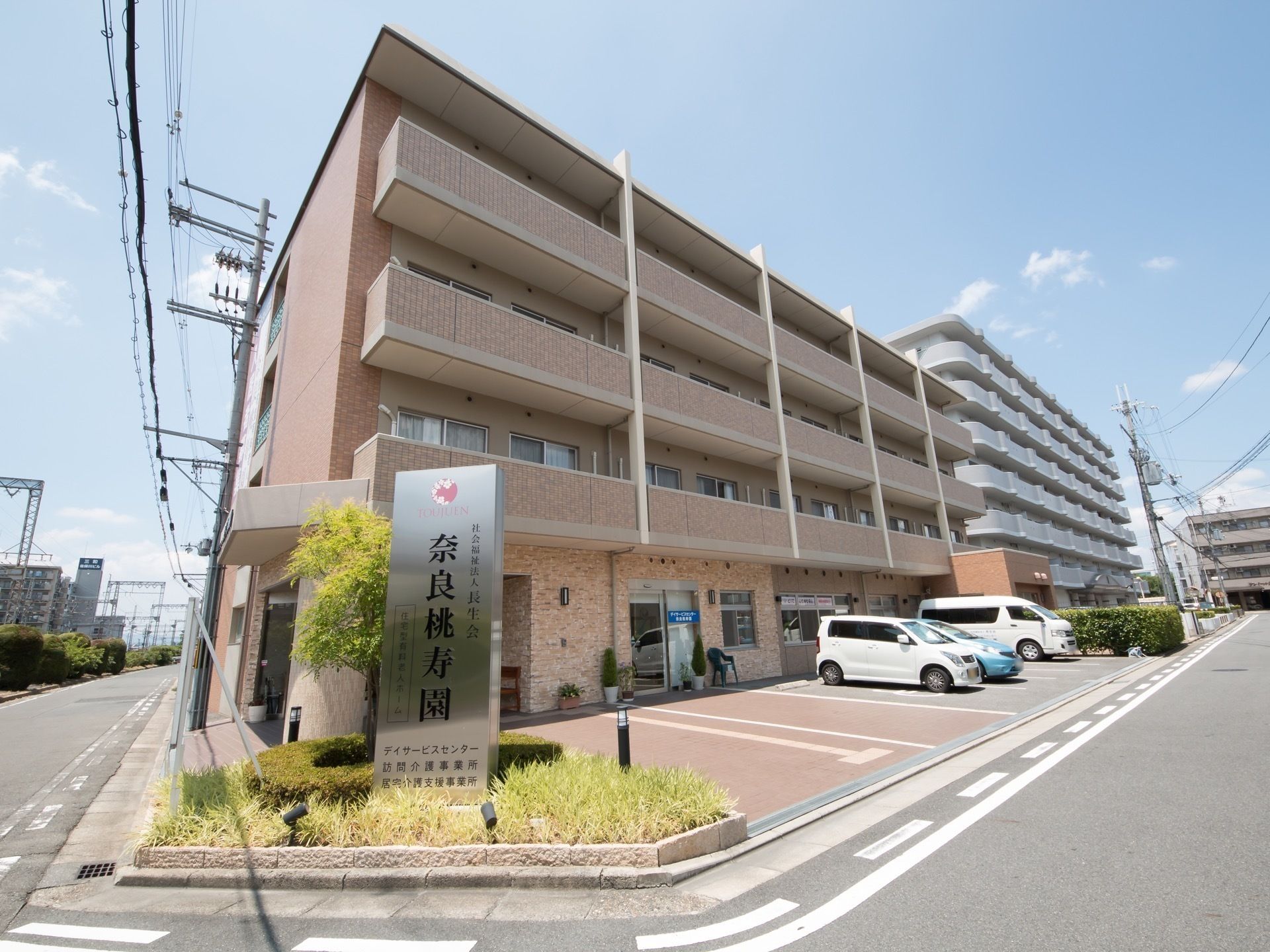 4階建てのピンク色の外壁が印象的な、道路に面した施設