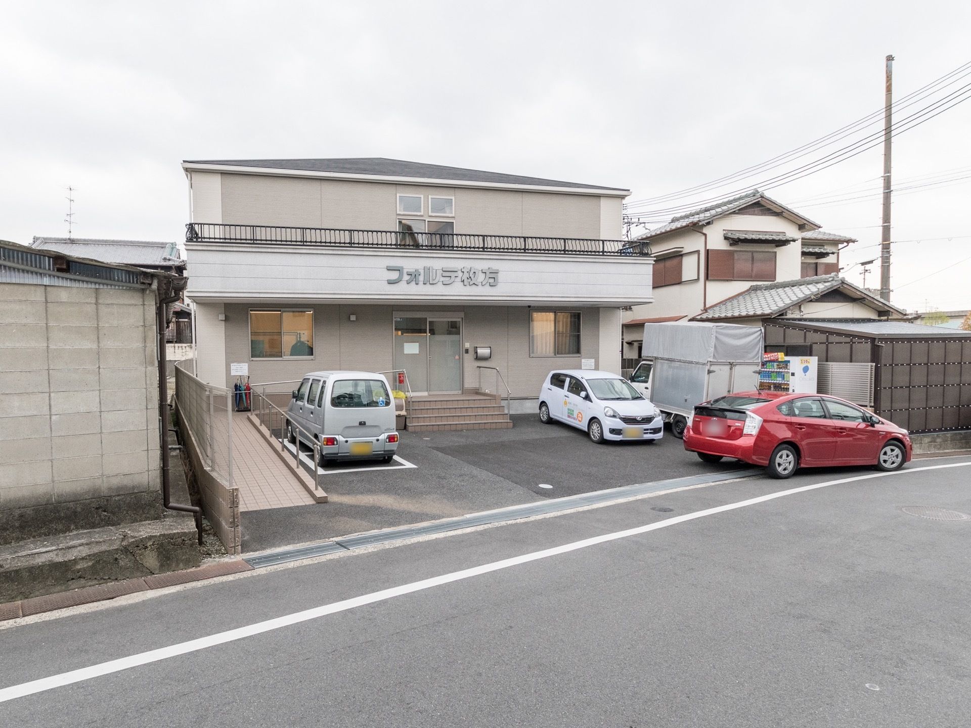 施設は閑静な住宅地の道路沿いに建てられている。駐車場から玄関までのアプローチはスロープが設置されている。