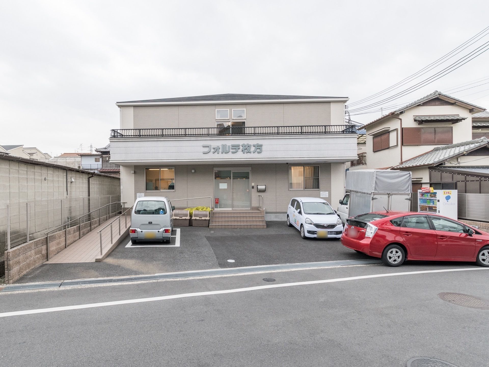 閑静な住宅地に立地している施設の外観。建物はこぢんまりとした2階建てになっている。敷地内に駐車スペースが設けられている。