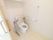 居室のトイレには、壁と便座の両脇に手すりが備わっている。背もたれ用パッドも付いている。上部にはトイレットペーパーなどを置く棚が付いている。