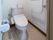 温水洗浄便座付きトイレがある。引き戸の木の扉がついている。壁には縦横方面につかまることができる手すりが設置されている。