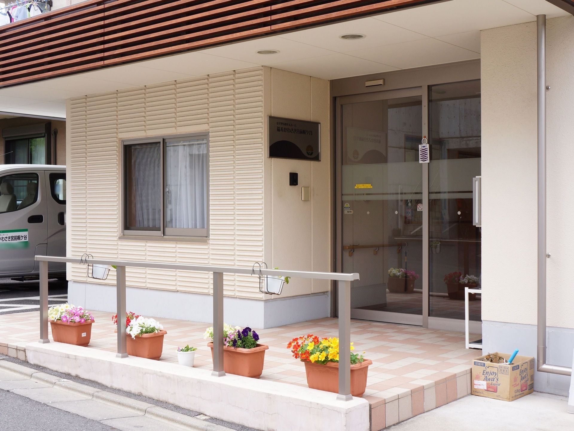 屋根付きのエントランスで、雨の日の出入りも安心である。プランタに色鮮やかに咲く花が植えられ、きれいに配置されている。