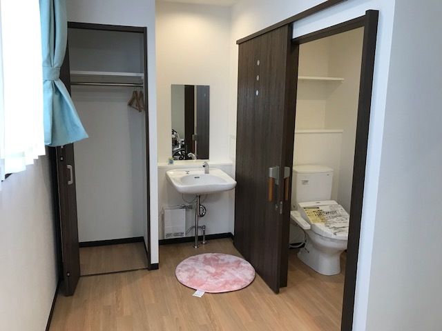 中央に手洗いがあり、左に扉の開いたクローゼットが、右に引き戸を開けたトイレがある。トイレとの間は段差がないバリアフリー設計になっている。