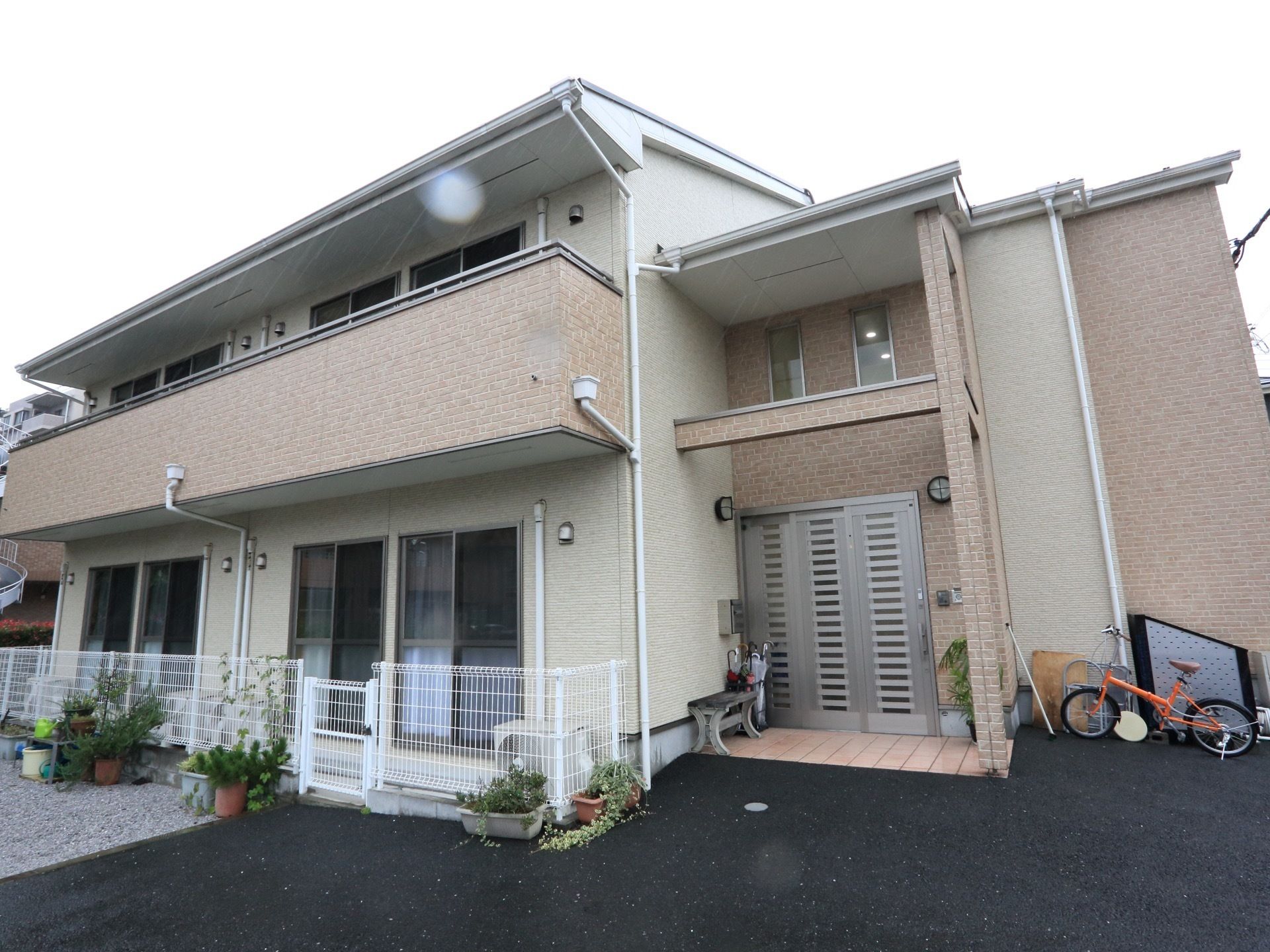 アパートのように窓が一定の間隔をおいて並んでいる。一階には、扉付きの簡易柵がある。柵の外側で植物を育てている。