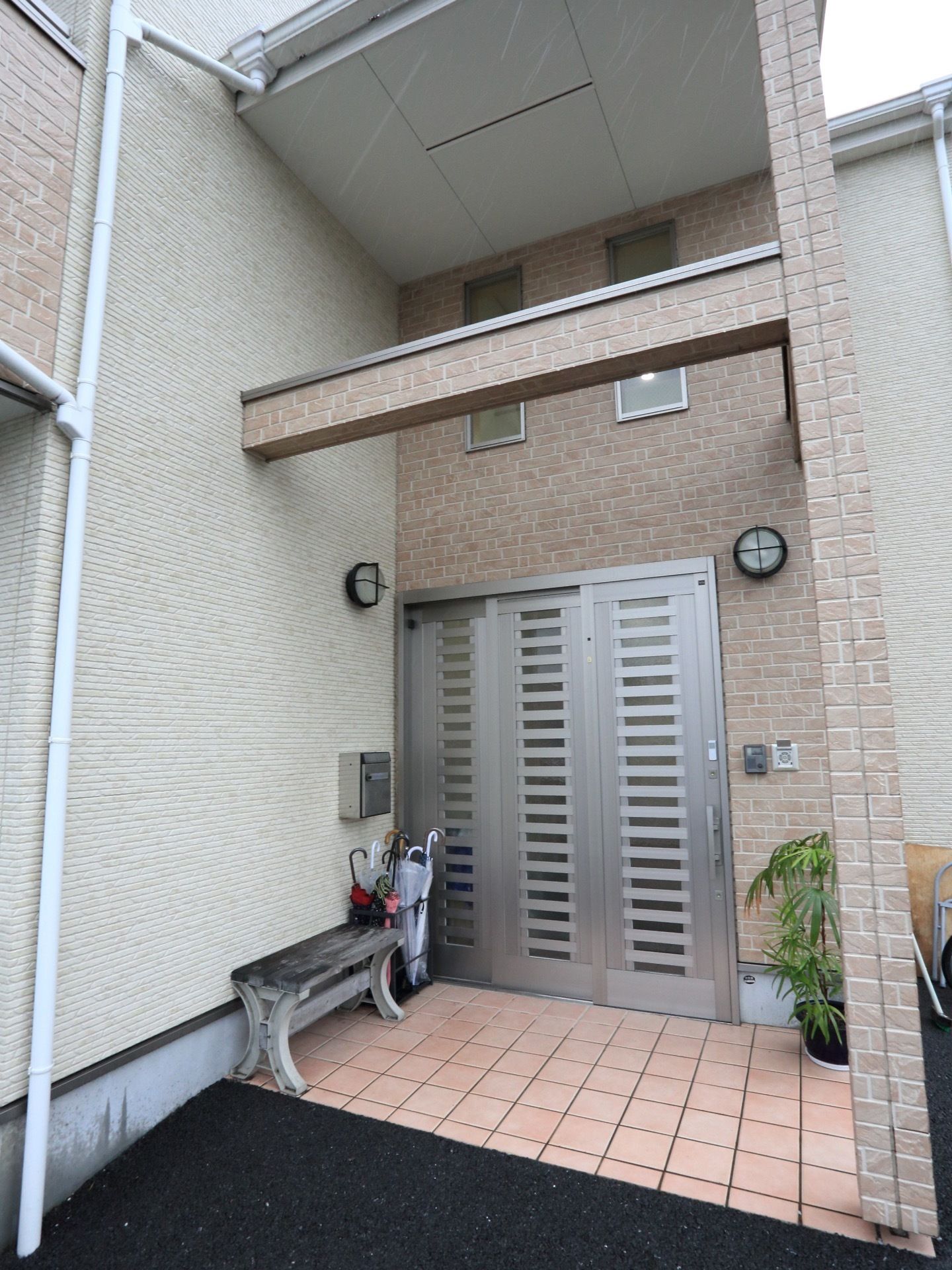 玄関前には、傘立てがある。またベンチも設置してある。屋根がついているので、雨の日に濡れずに傘をたたむことができる。