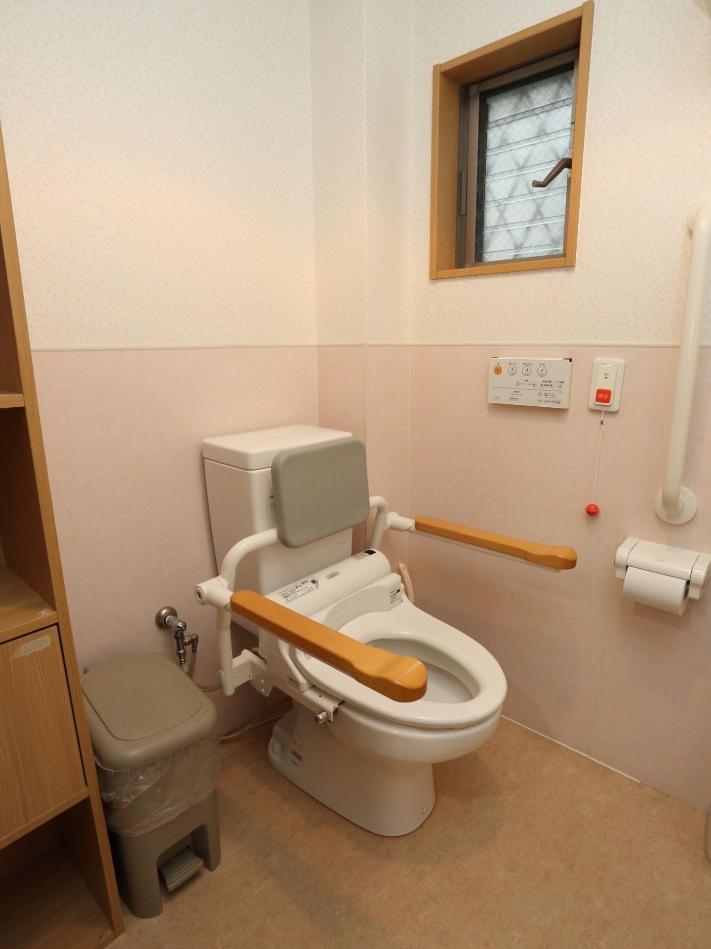 トイレには、ナースコールがありボタンと紐を引き作動させることができる。背もたれと肘置きがあり、体を支えるつくりである。