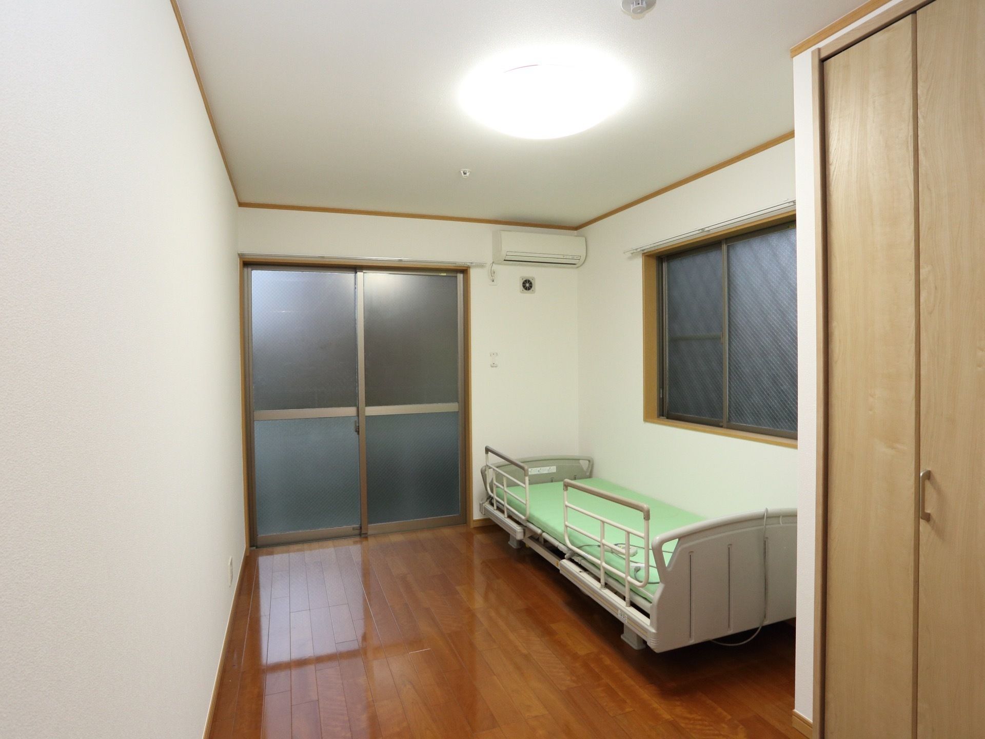 広く、シンプルな部屋になっている。電動式のベッドが置かれている。クローゼットが作り付けになっている。