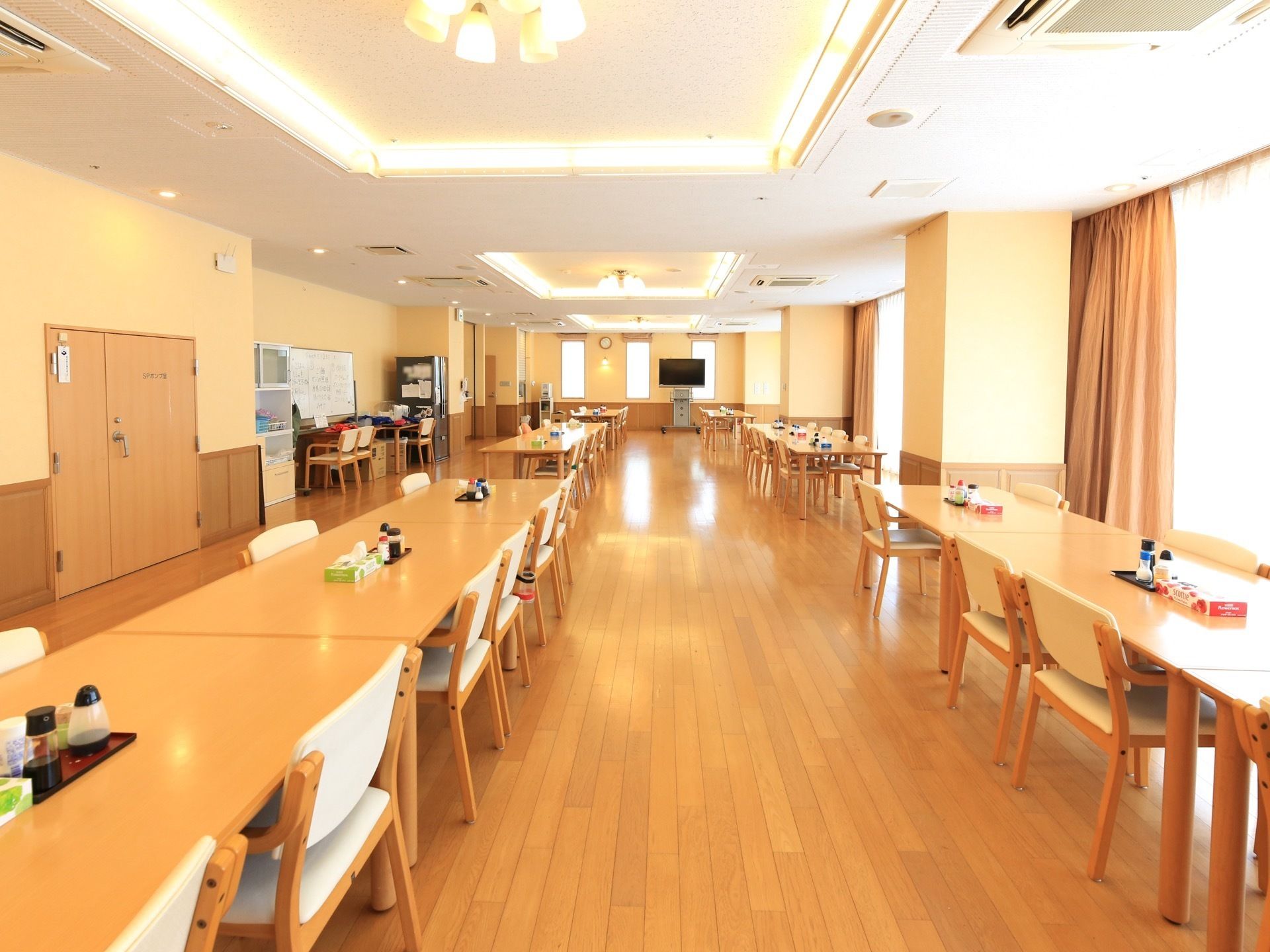 食堂は広々としていてフローリング張りである。テーブルが２列に配置されていて、席と席の間は広く取られている。