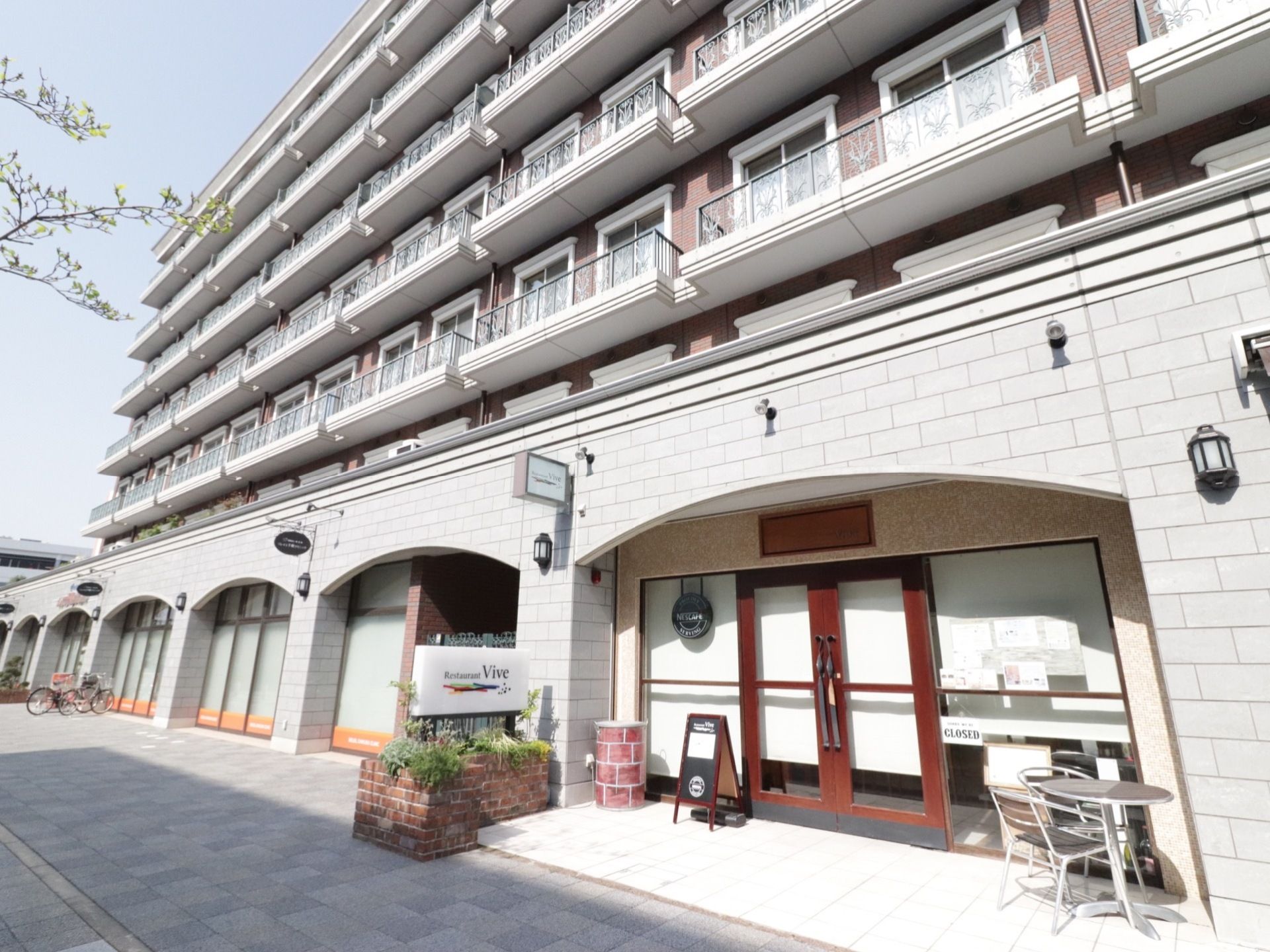 １階はレストランとなっており、外に看板とテーブルが置いてある。２階以上が居室となっており、ベランダが各居室で分かれている。