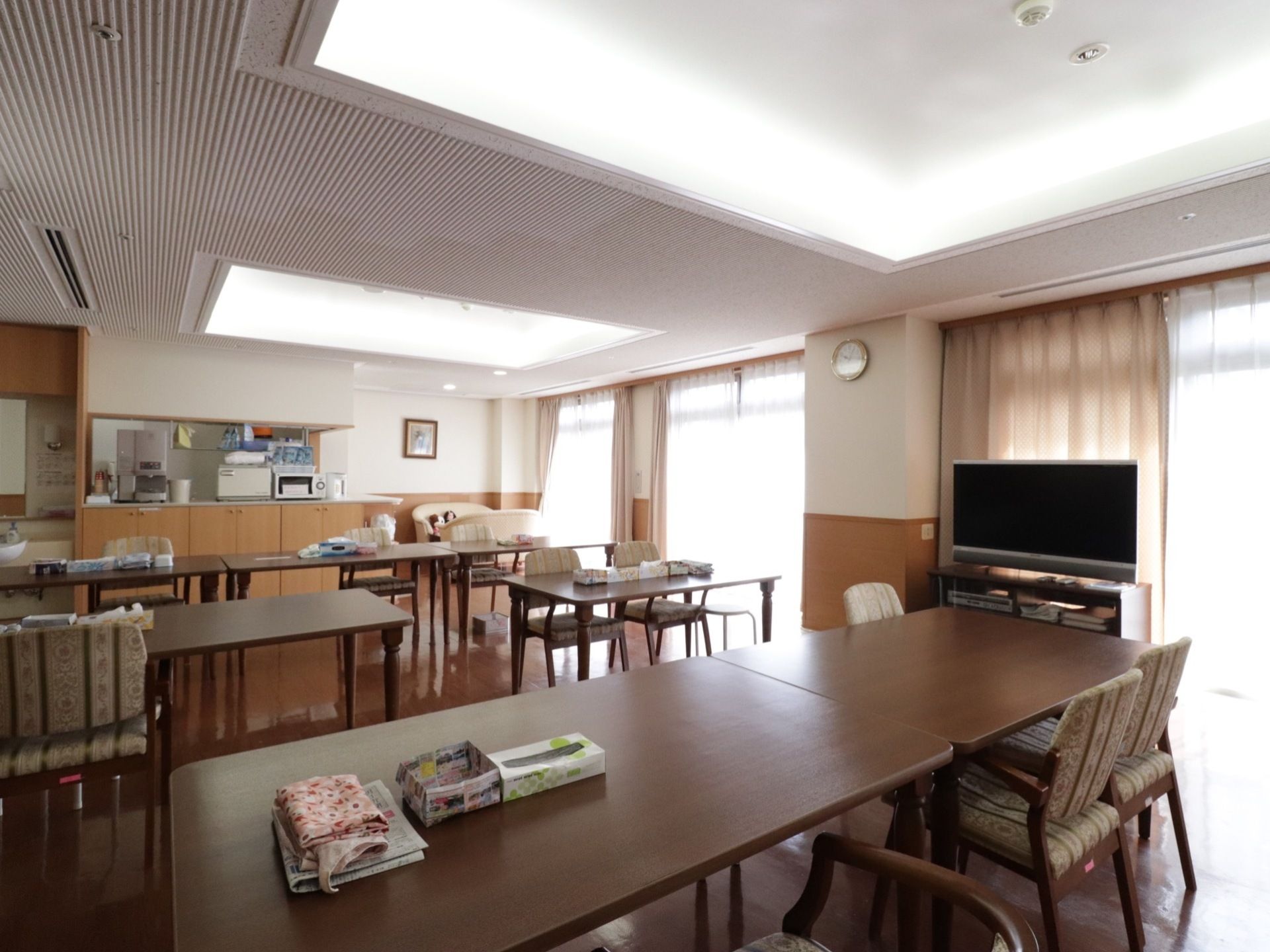 キッチンには電子レンジやポット、給水器がある。リビング側にはテーブルとイスが配置されており、ティッシュが置いてある。