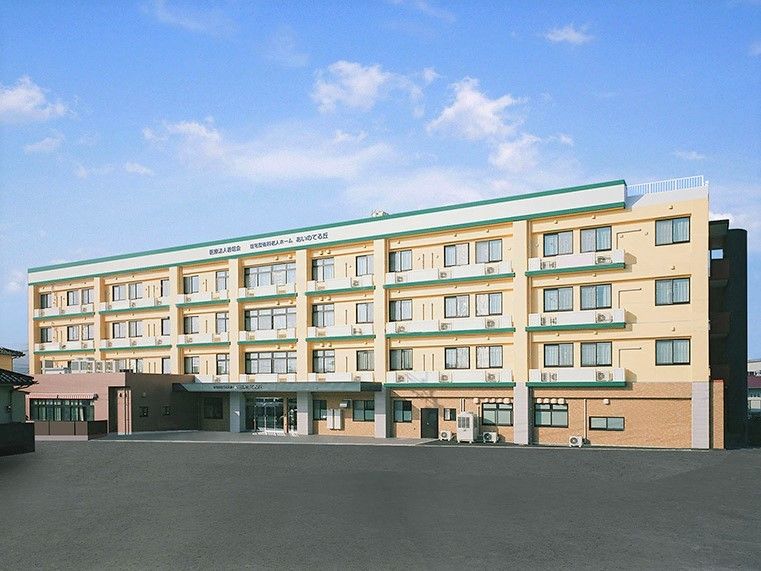 施設は4階建ての大規模な建物。個室の窓が並んでいる。明るい色の外壁のため、建物の大きさの割に圧迫感はない。
