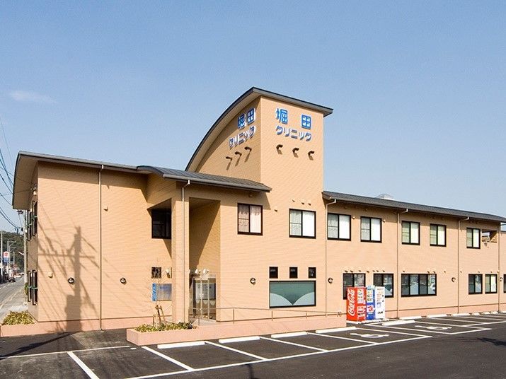 黄色い外壁の2階建ての建物の前にある、10台以上の駐車場