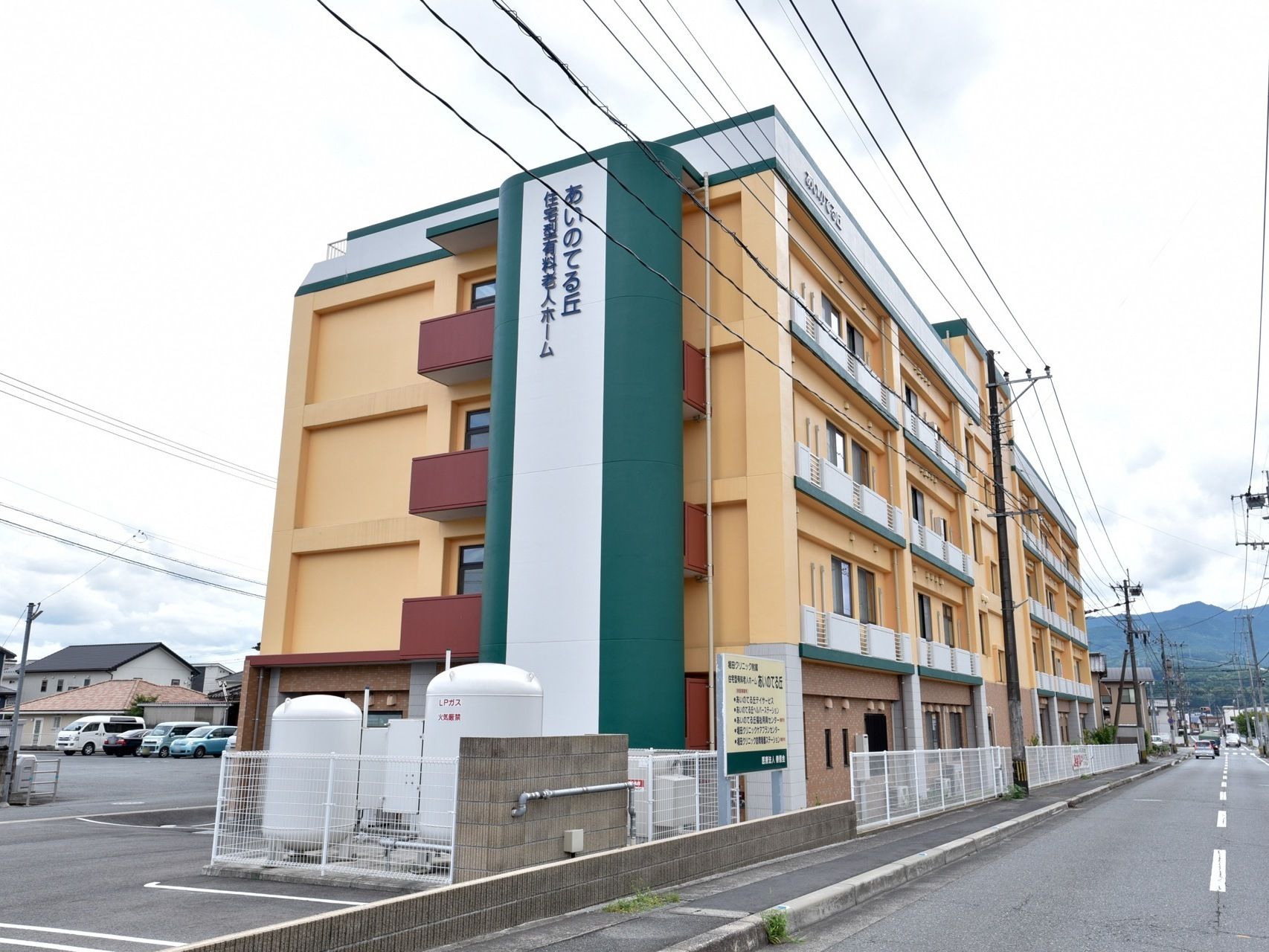 カラフルな色使いの４階建ての施設である。４階まで続く壁面に縦書きで大きく施設名が表示されている。敷地内に駐車場がある。