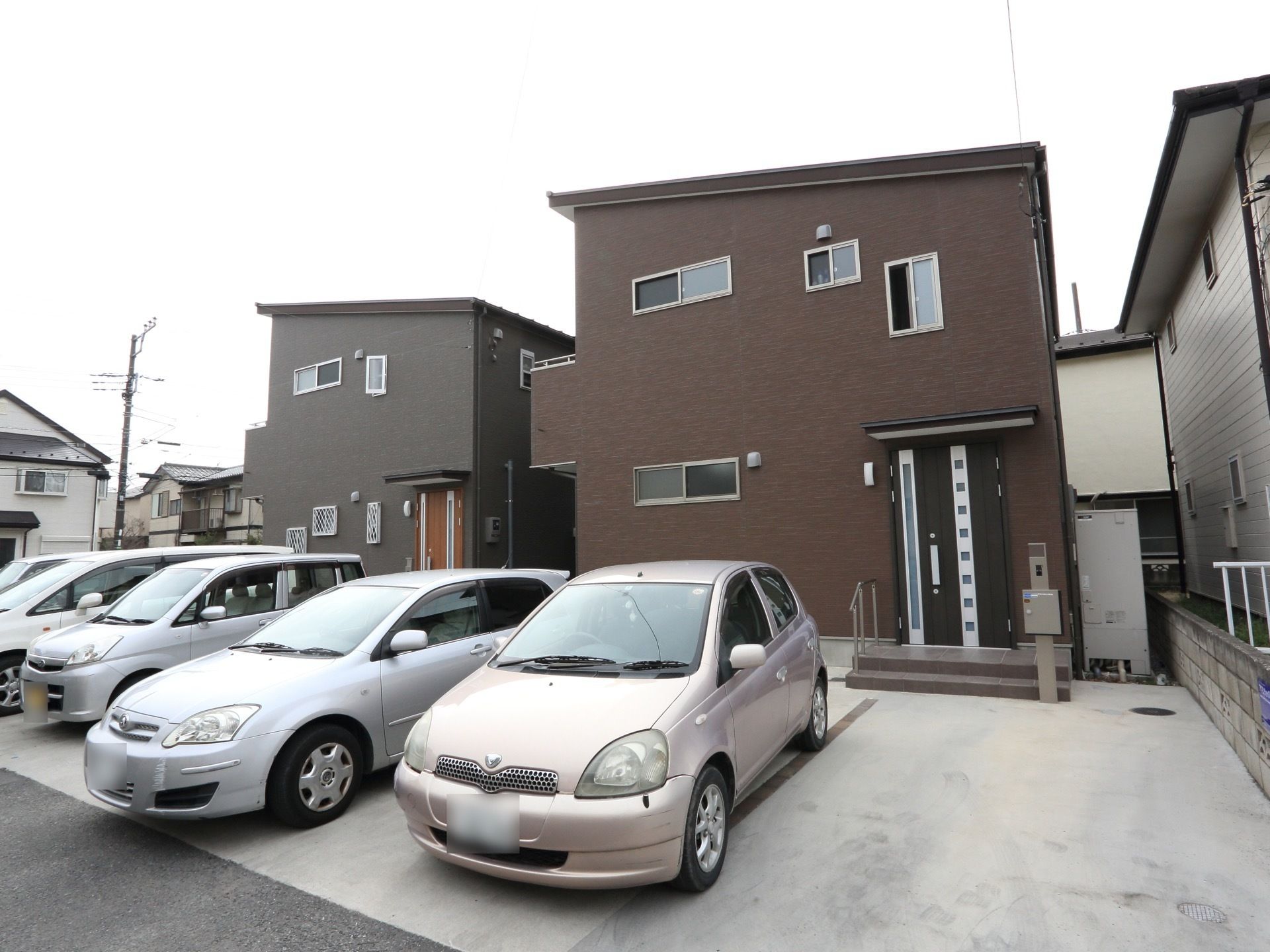 外観は戸建住宅と変わらず、住宅地に馴染んでいる。ドア前には駐車スペースもある。２階建てで濃い茶色い外壁である。