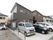 施設の建物は、傾斜のある屋根と濃いグレーと茶色の外壁が特徴的である。窓枠は白色で、片側が開く小窓もある。