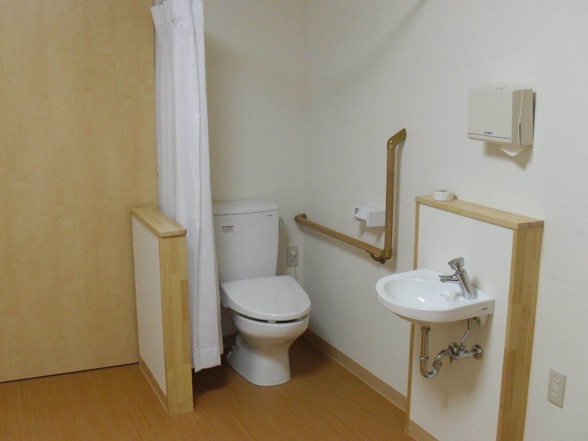 シンプルな手洗い場が設置されており、ペーパータオルが準備されている。トイレはカーテンで仕切られるようになっている。