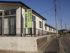 落ち着いた住宅街の中にあるグループホームである。建物の横には、施設名が書かれた看板が立てられている。