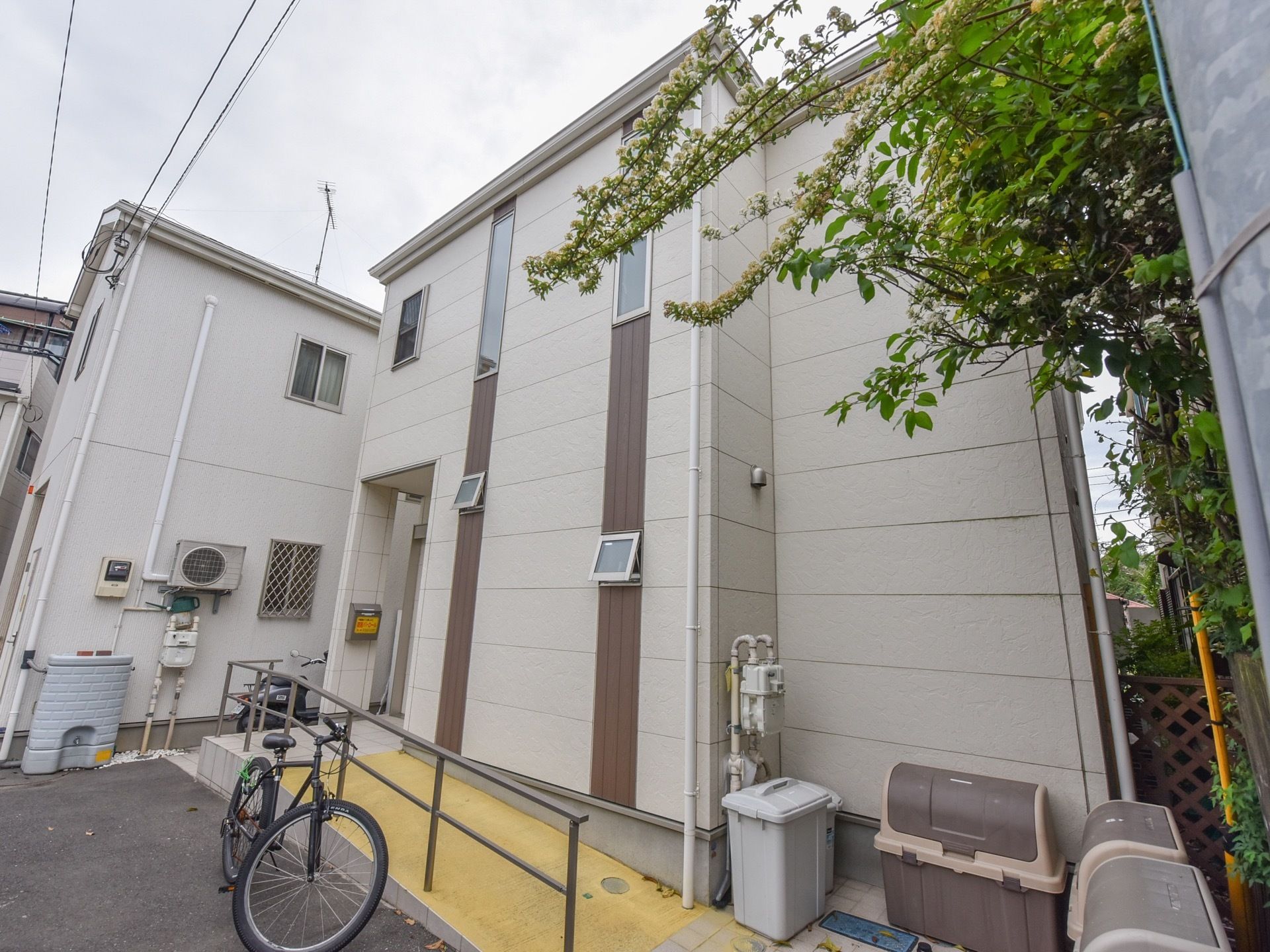 白を基調とした建物で、２階建ての構造になっている。扉前にポストがあり、入口前には分別用のゴミ箱が３個置かれている。