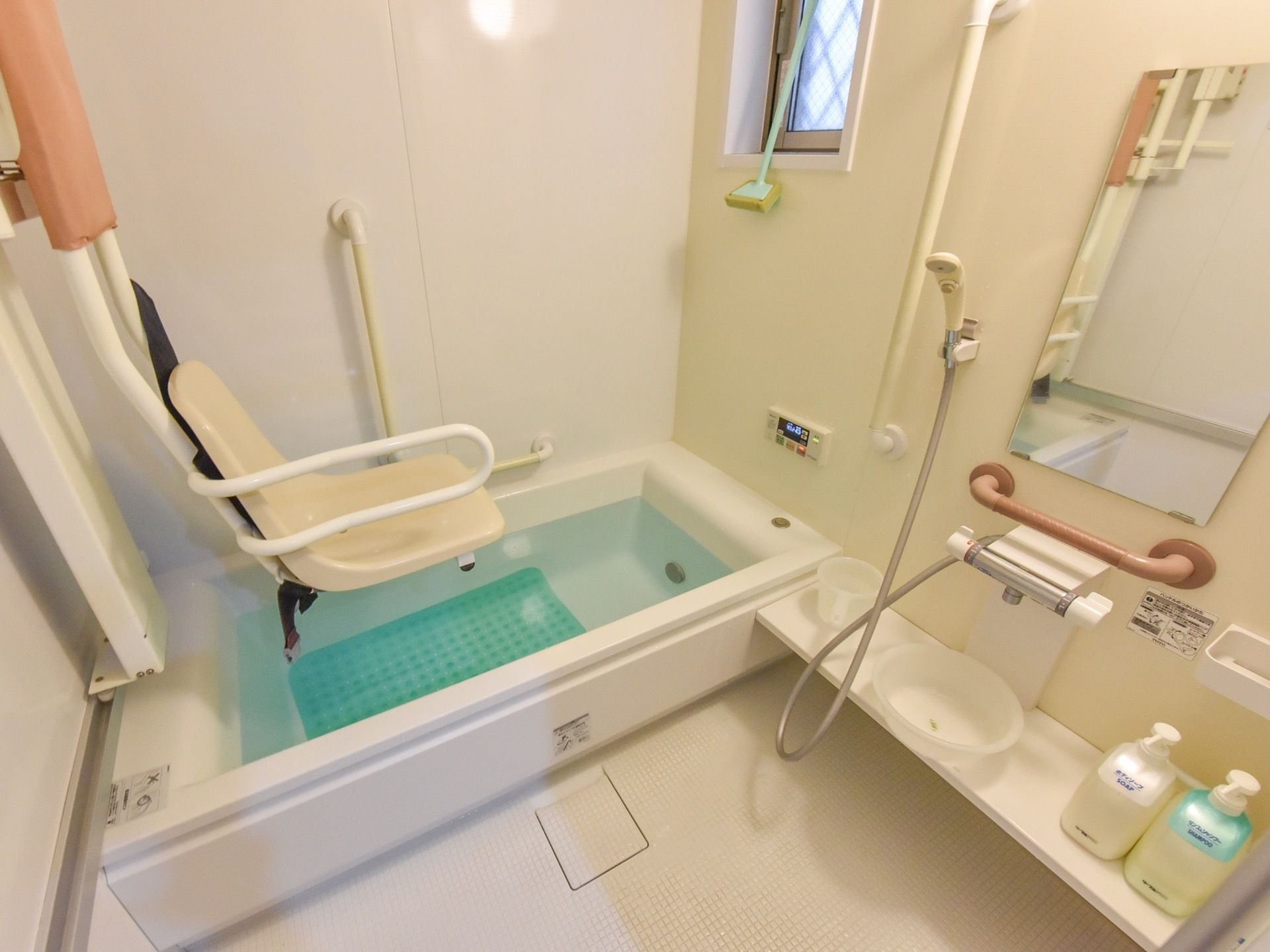 個浴用浴室にはリフト式の介護用椅子が設置されている。洗面器と手桶、ボディソープとシャンプー類が備え付けられている。