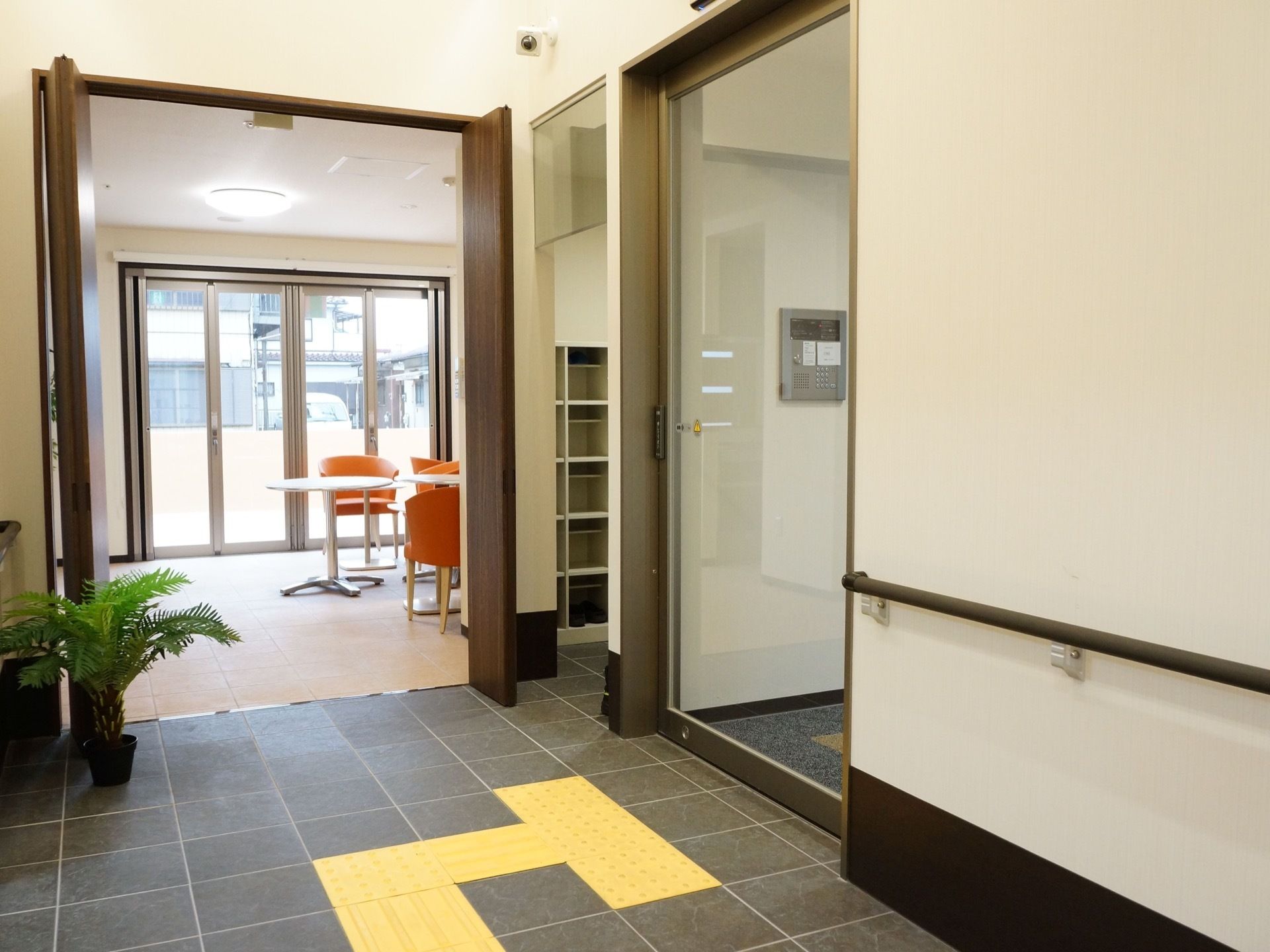 扉は自動ドアになっており、ボタンが付いている。手すりや点字ブロックが設置されている。奥には休憩スペースがある。