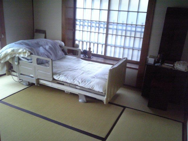 畳敷きの和室タイプの居室である。ガラス障子が取り付けられた窓際には、介護ベッドが置かれている。壁際に鏡台が設置されている。
