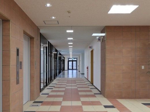 エレベーターホールからつながる廊下の右側にはトイレがある。左側にはガラス引き戸がならび、各種の部屋が区切られている。