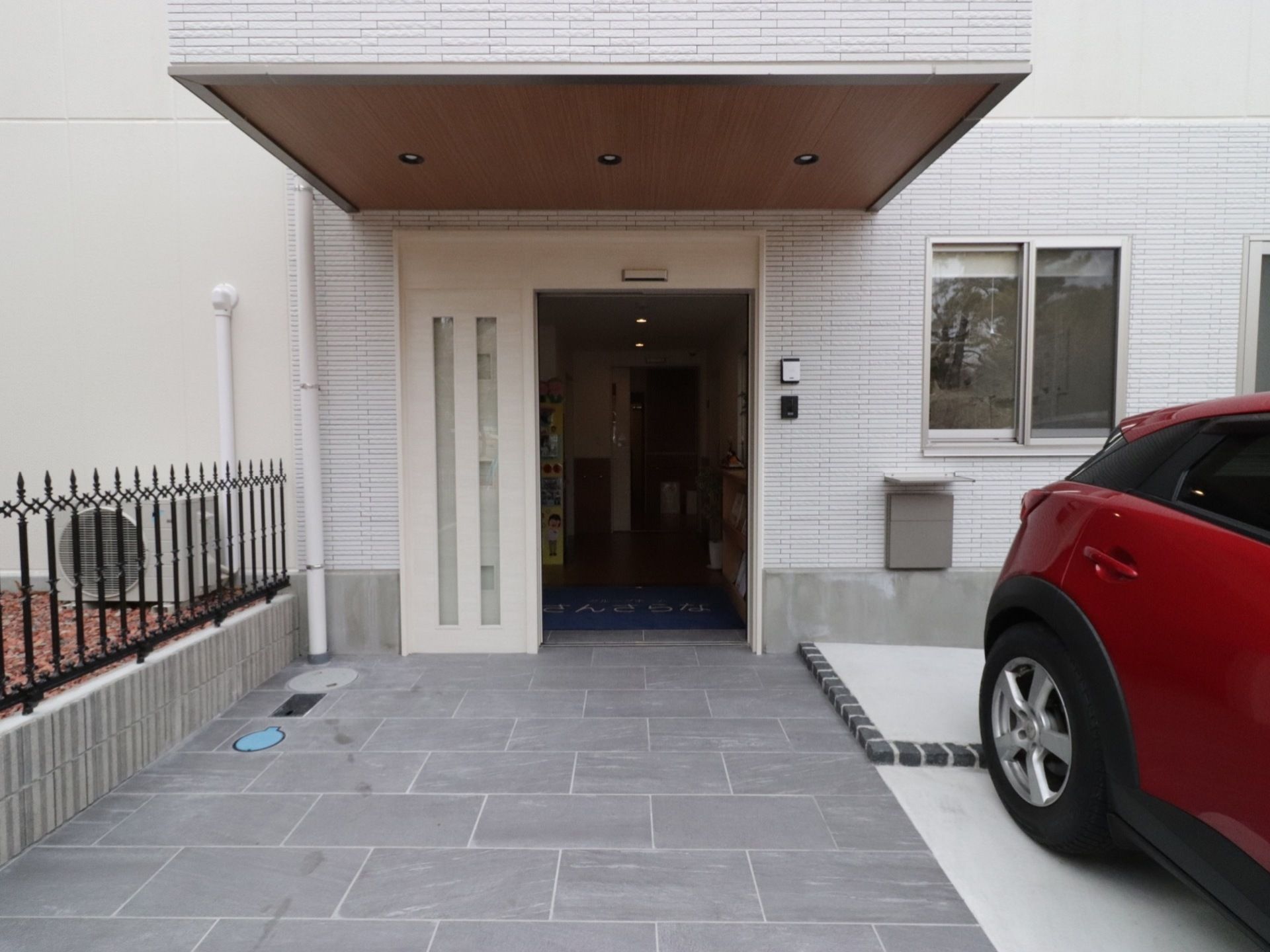 大きな屋根が完備された白を基調としたエントランスである。目の前に駐車スペースがあるので移動が便利である。