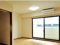 エアコンが完備されたシンプルな個室である。黒い枠が特徴的な大きな窓が取り付けられており、ベランダへ出られるようになっている。