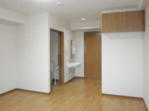 入口そばに洗面台とミラー、中には吊戸棚が設置された空き部屋