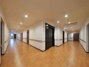 通路は広く、複数の入居者様が通行しても余裕がある。また、掴まって歩いていただけるように手すりもある。