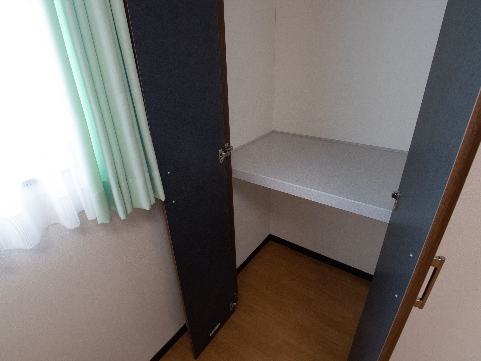 居室内にはクローゼットがある。観音開きの黒い扉で、中には仕切り板があり、上下に収納ができるようになっている。