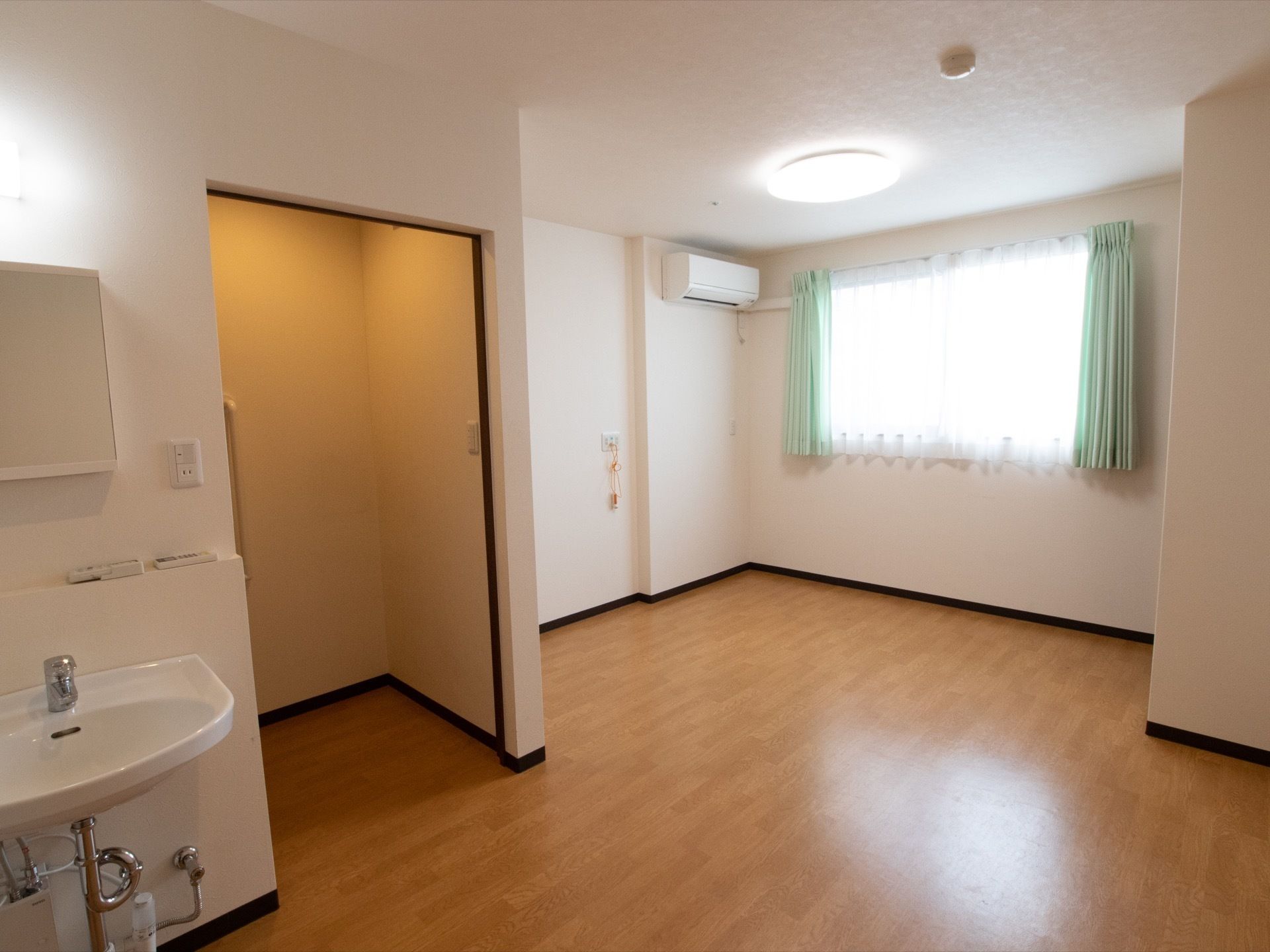 白壁の明るくて清潔感のある居室の様子。トイレの扉はスライド式なので、場所を取らず開閉も楽に行っていただける。