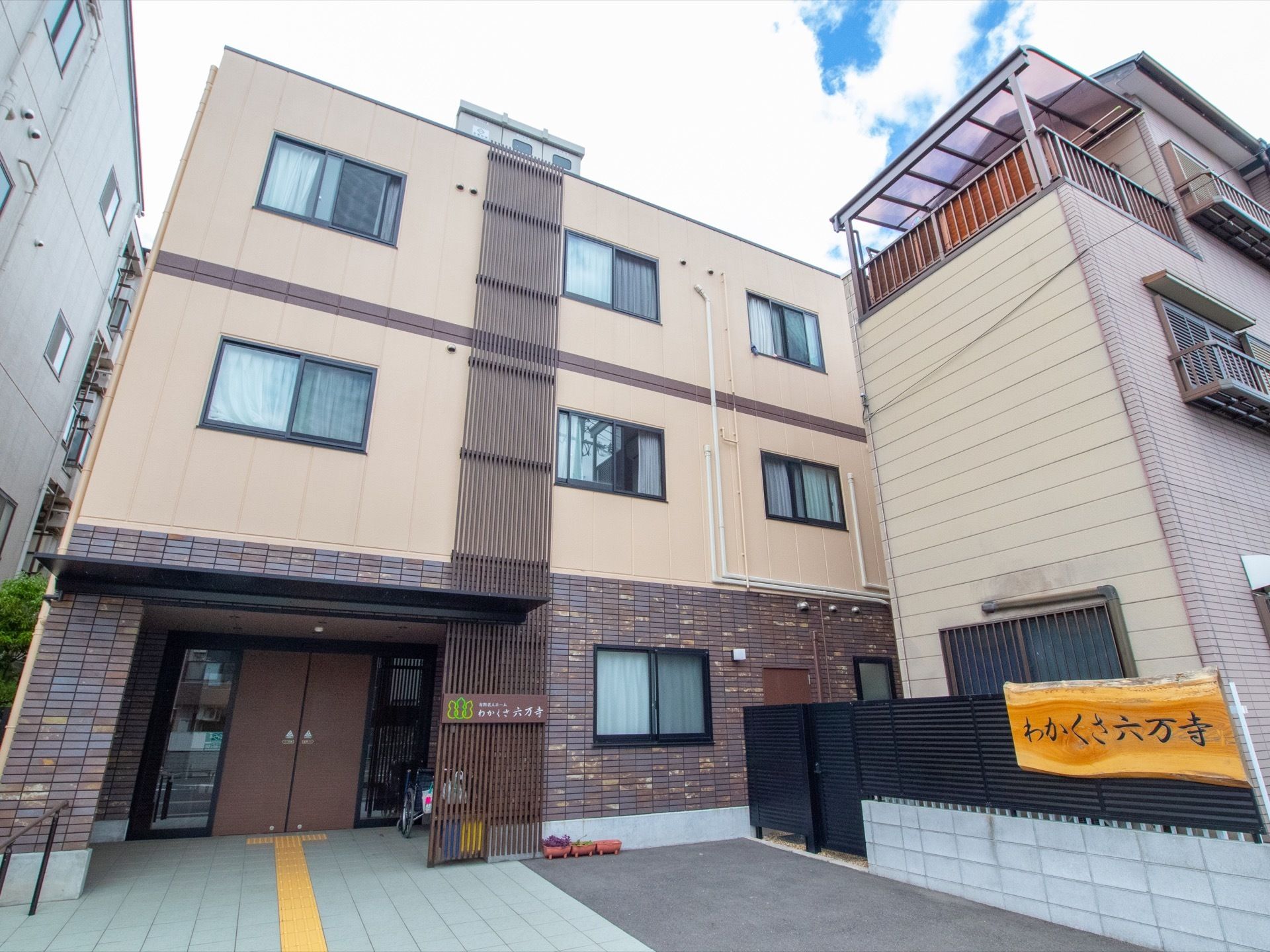 周りの住宅地に溶け込んでいる、３階建て施設の外観。散歩の際には、地元の人との交流も楽しみの一つである。