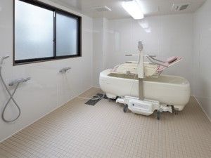 介護用リフトが設置された、白壁と白い床の広いバスルーム