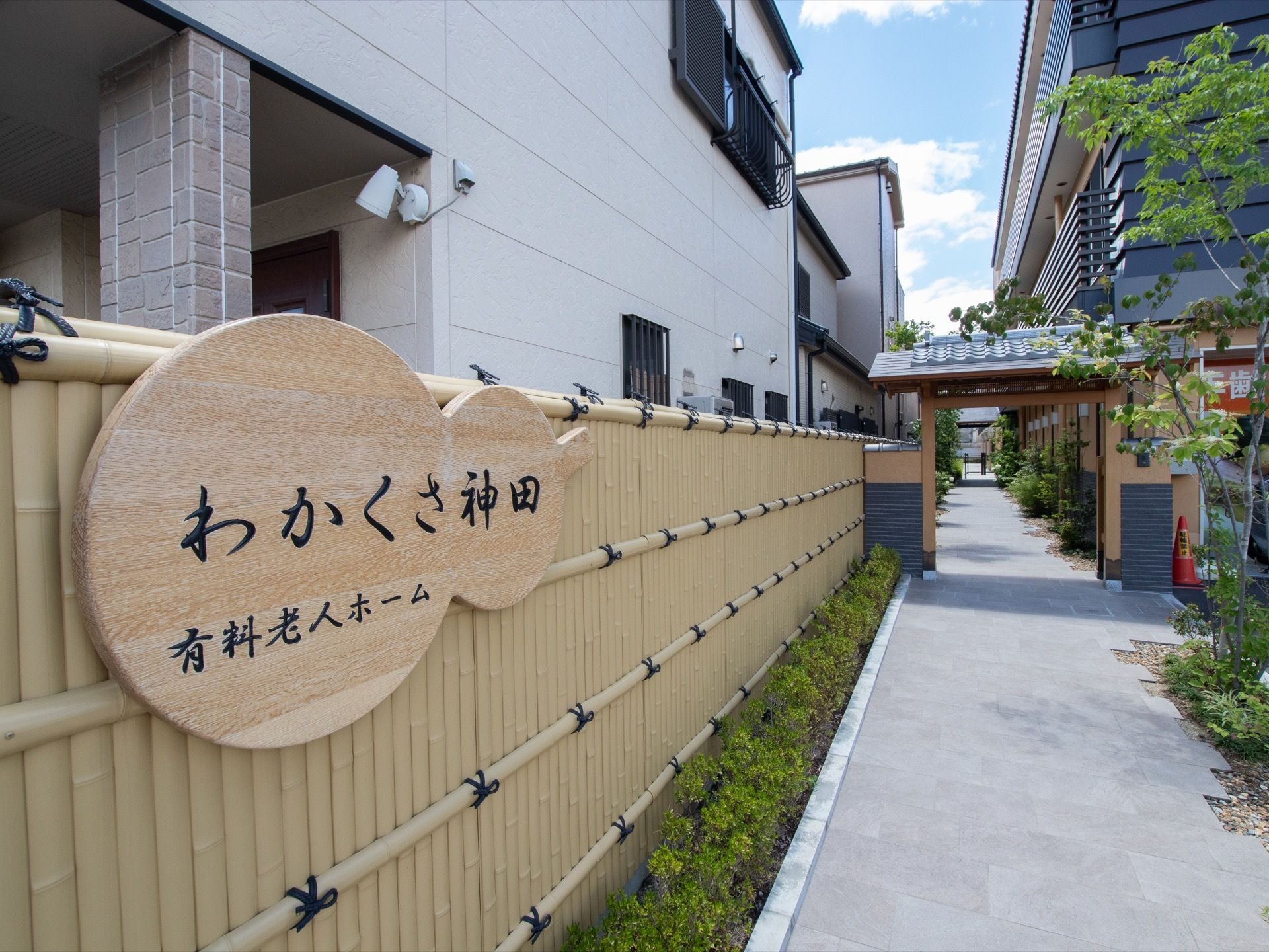 竹垣風のフェンスに掲げられた施設の看板は、施設のトレードマークである瓢箪の形のプレートに、毛筆体で施設名が書かれている。