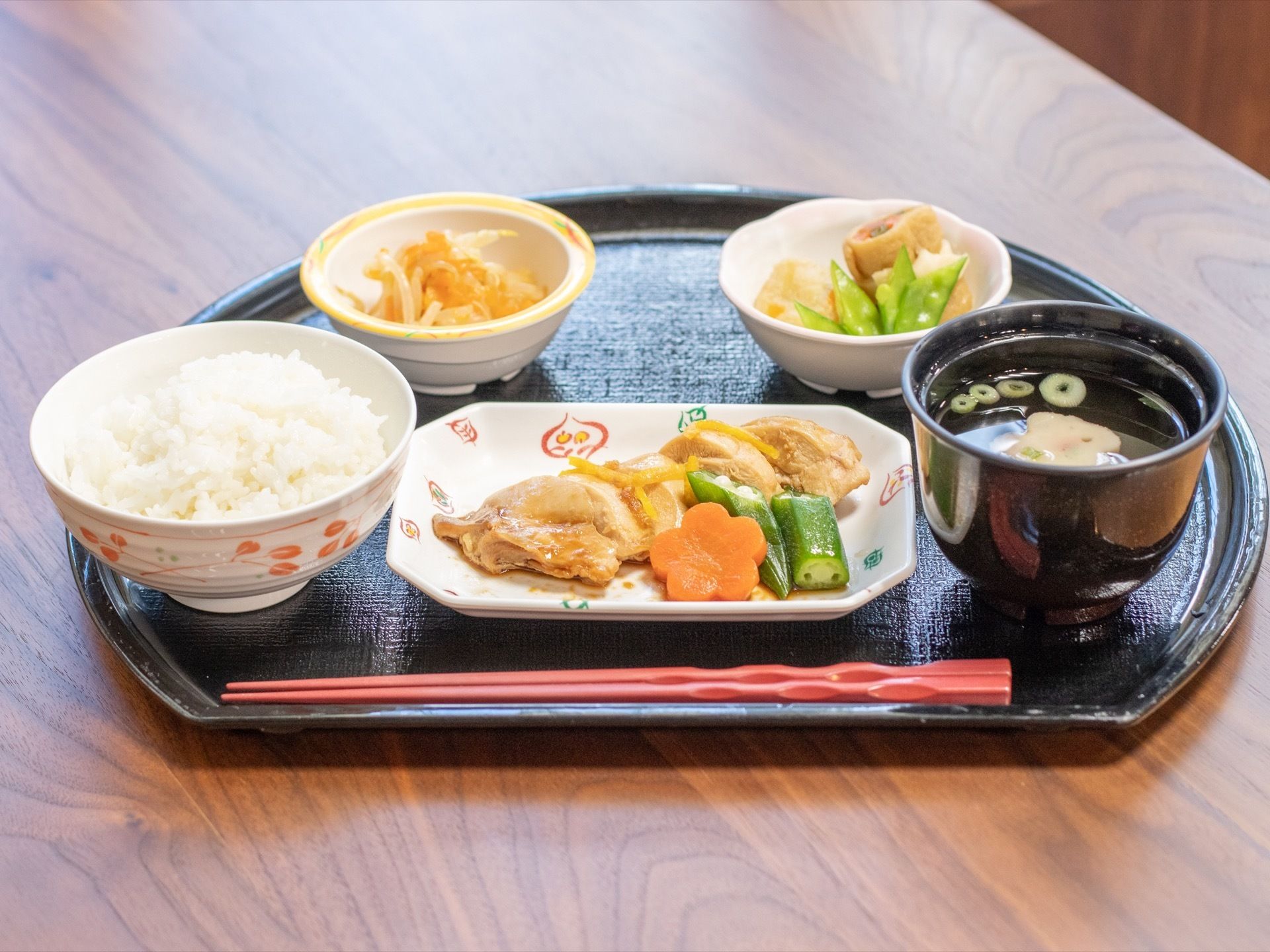 黒塗りの半月膳に食事がセッティングされている。この日の献立は、ごはんに汁物、主菜、副菜２種で構成されている。