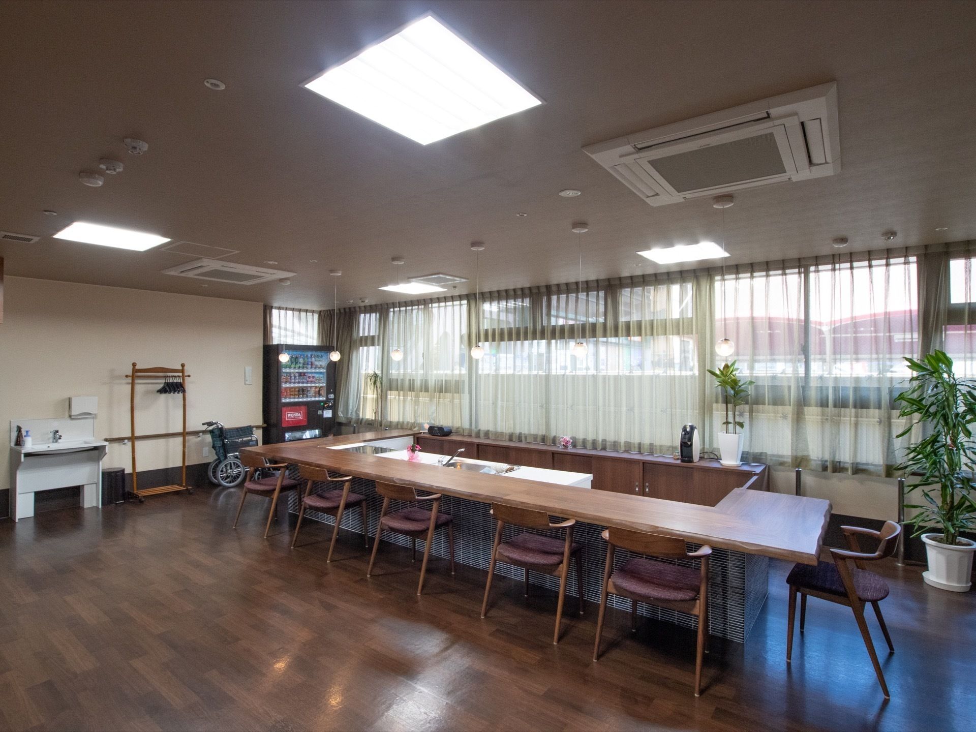 アイランドキッチンを囲むウッドカウンターにおしゃれなチェアが並ぶ、カフェのような空間