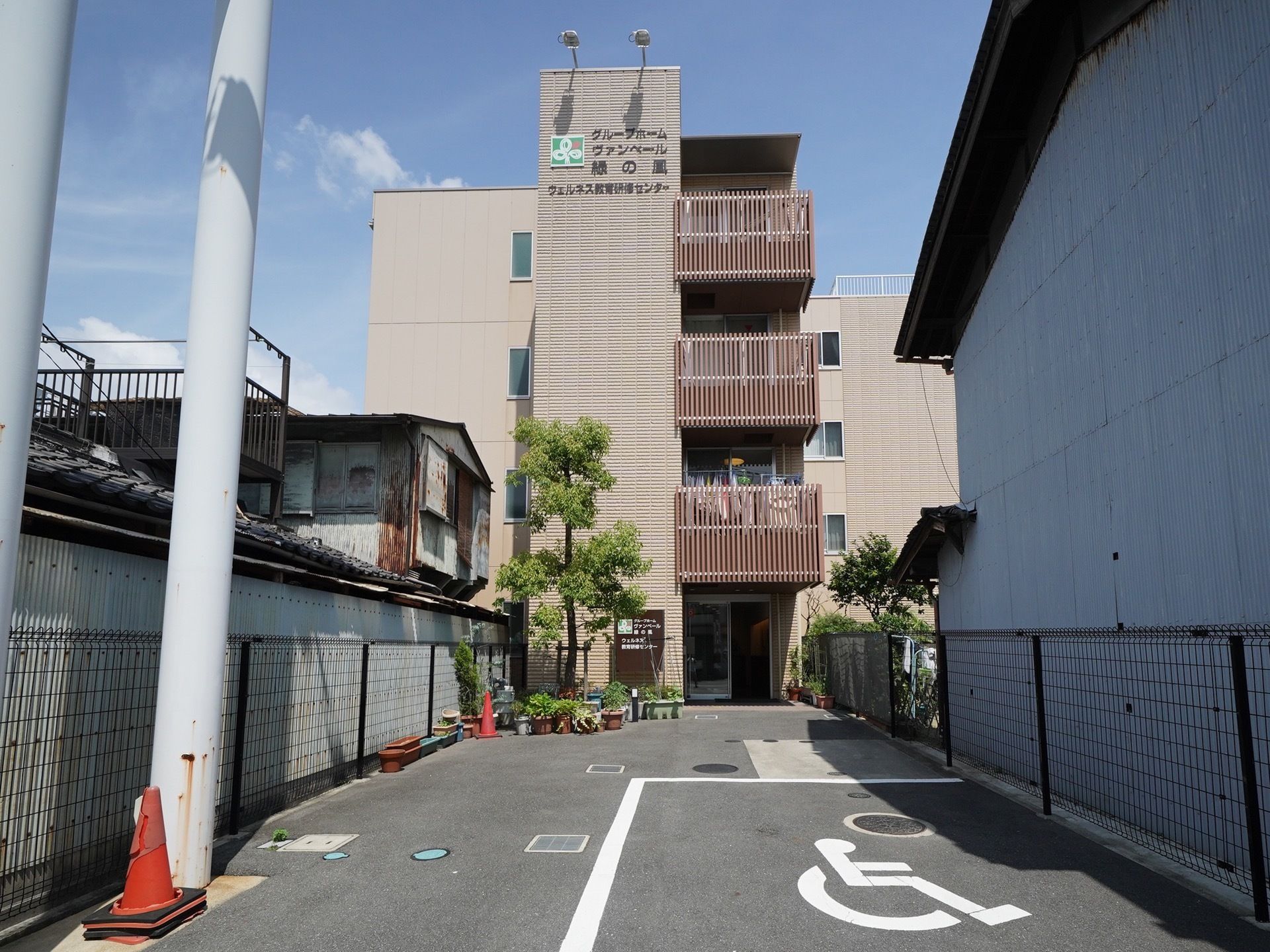 道路から少し奥に入った場所に建てられている４階建ての建物である。日当たりの良いベランダがある。手前に駐車スペースがある。