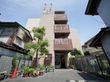 ライトブラウンのタイル張がシックな印象の４階建である。戸建て住宅の並ぶ周囲の環境にもよく馴染んでいる。