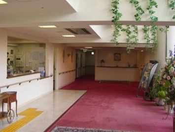 受付前のフロアには花が飾られている。また、チラシも置かれている。受付横には茶色の台が置いてある。手すりもついている。