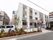 街中に建つ3階建ての建物である。静かな街中に位置している。玄関前には数台分の駐車スペースがあり車が停められている。