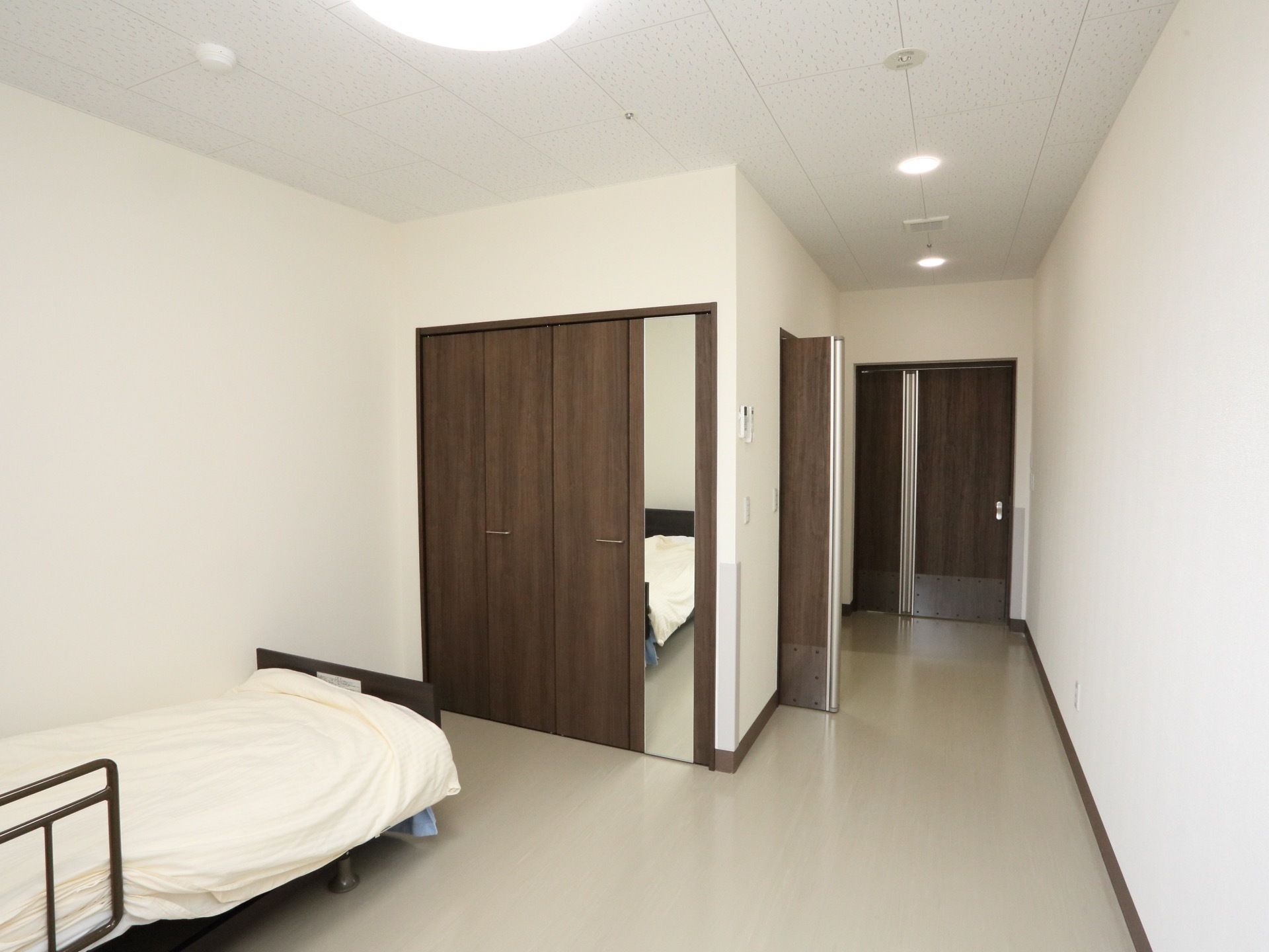 広々とした居室になっている。白い壁で清潔感があり、モダンな雰囲気になっている。鏡があり全身の身だしなみのチェックをすることができる。