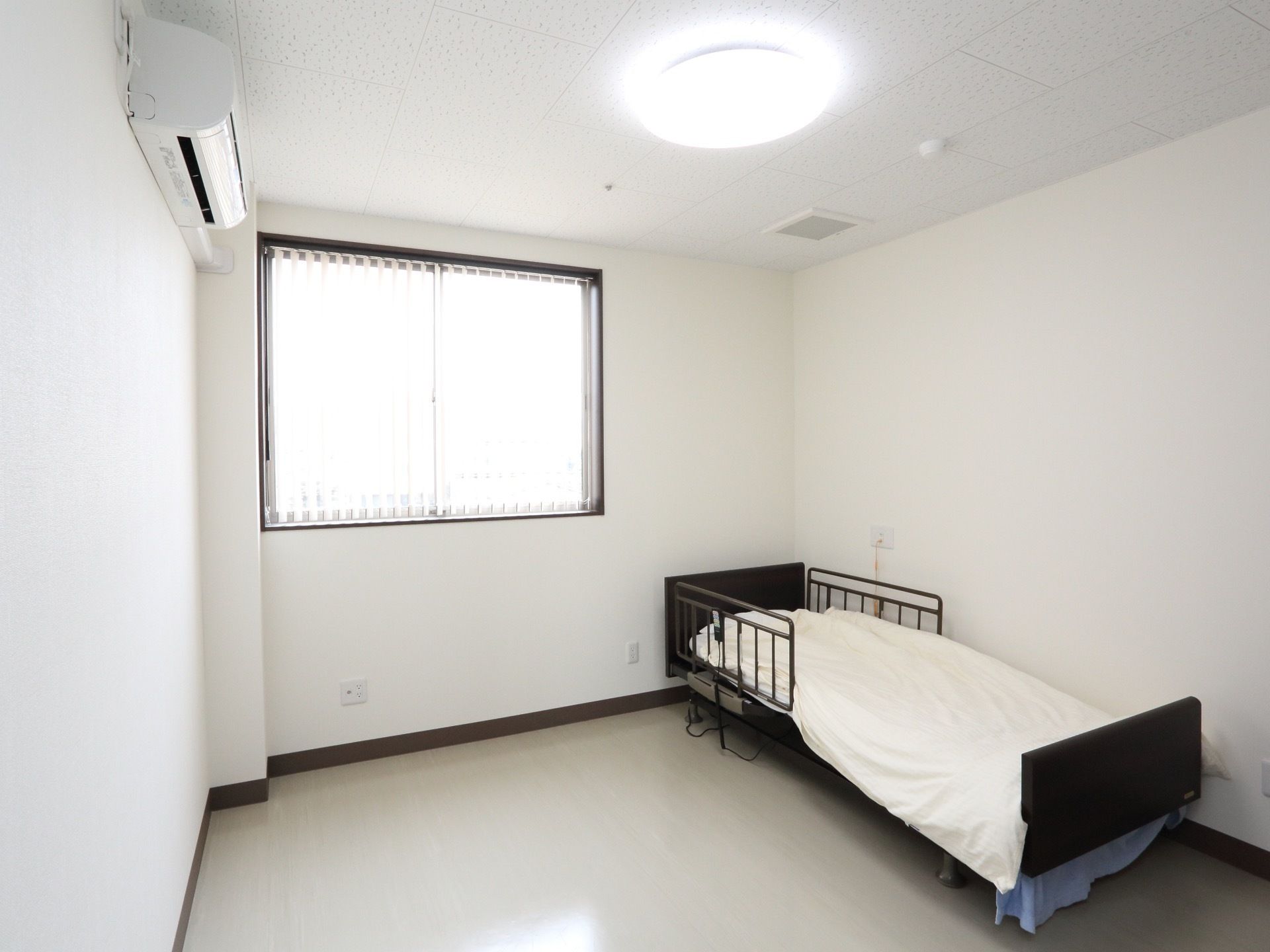 白で統一され、エアコンと落下防止用の柵がついたベッドのある居室