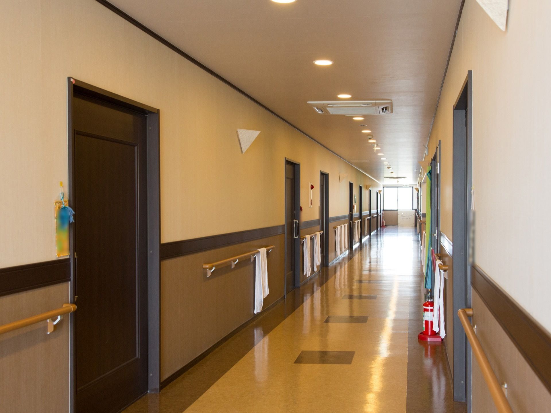 通路はまっすぐに続いている。通路の両側には部屋の扉と手すりがずらりと並んでいる。床には消火器が置かれている。