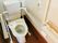 跳ね上げ式の肘置きや背もたれが付いた、バリアフリータイプの洋式トイレである。壁にはナースコールが設置されている。