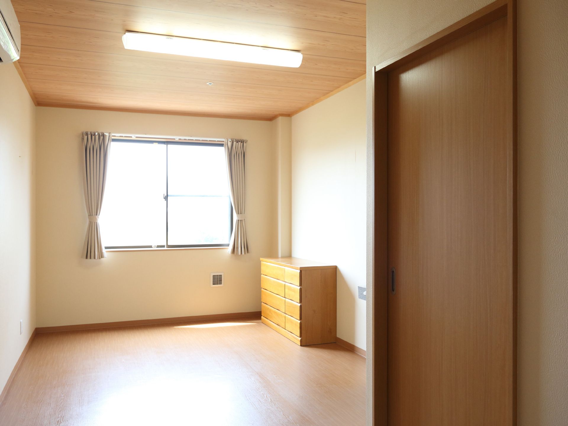 エアコンと、衣装棚が設置され、窓からの光と大きな照明で明るい居室