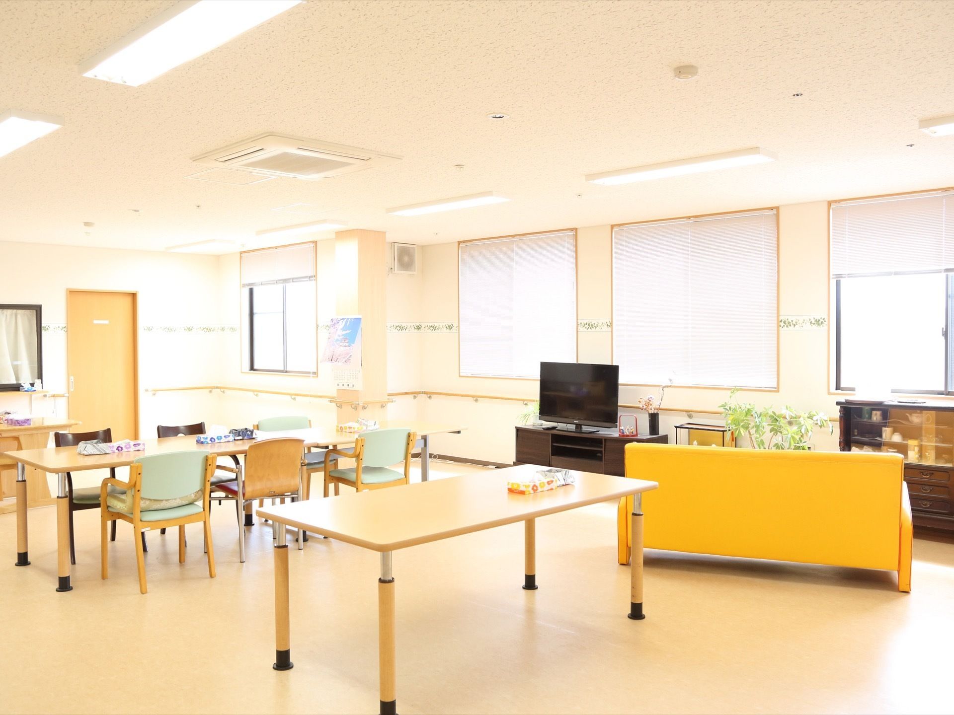 広い空間にテーブルや椅子、ソファが置かれている。窓が多く設置されていて、壁には手すりが設置されている。