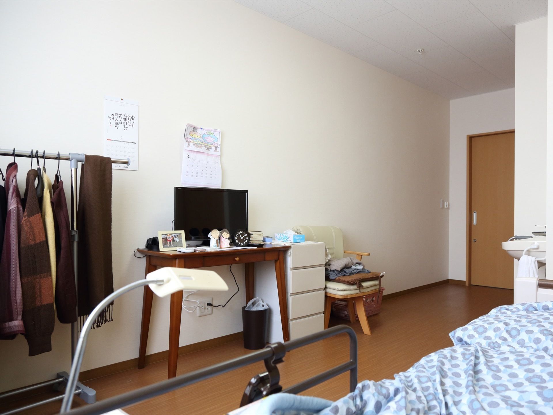 白を基調とした壁である。床はフローリングで縦長の部屋の造りである。ベッドや引き出しなどのちょっとした家具が置かれている。