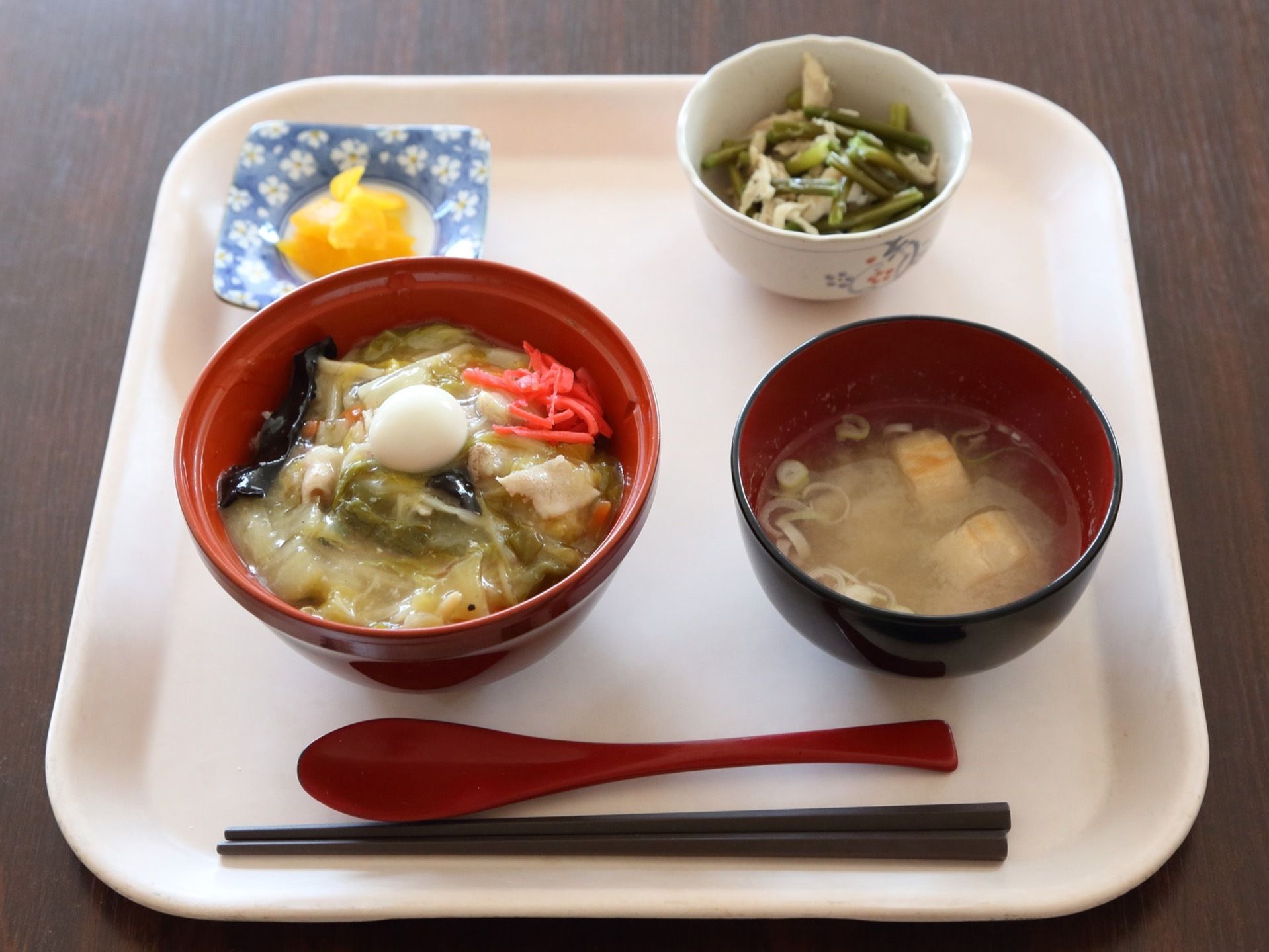 主食と副菜や汁物が、箸やレンゲと共に盆の上に置いてある。野菜をたくさん使用していて、色鮮やかである。